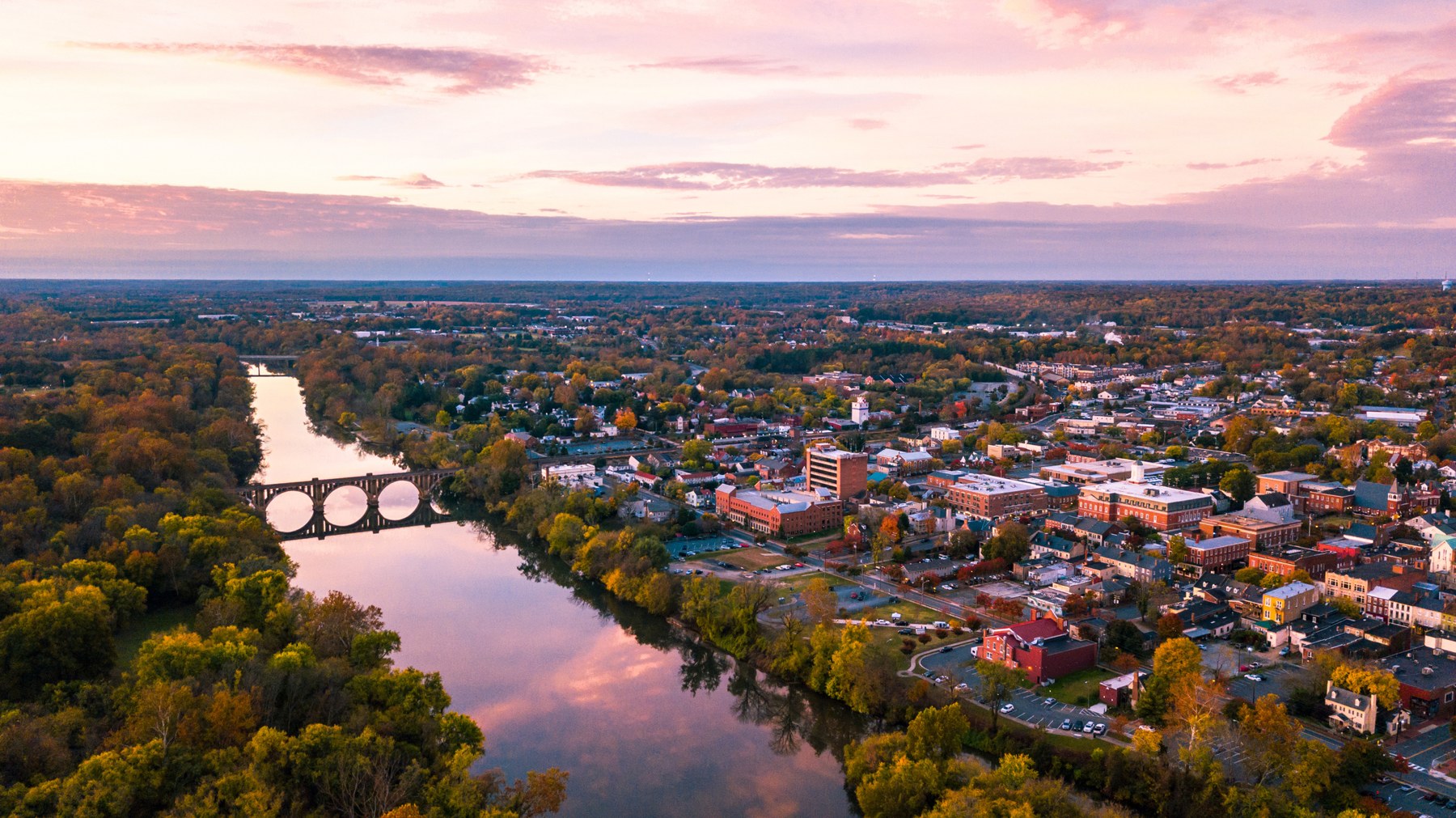 A river winding through a tree-lined town at sunset, from Paige’s relocation guide